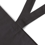 Close-up of black cotton canvas tote bag stitching and sturdy 20'' handles. Designed for durability and everyday use.